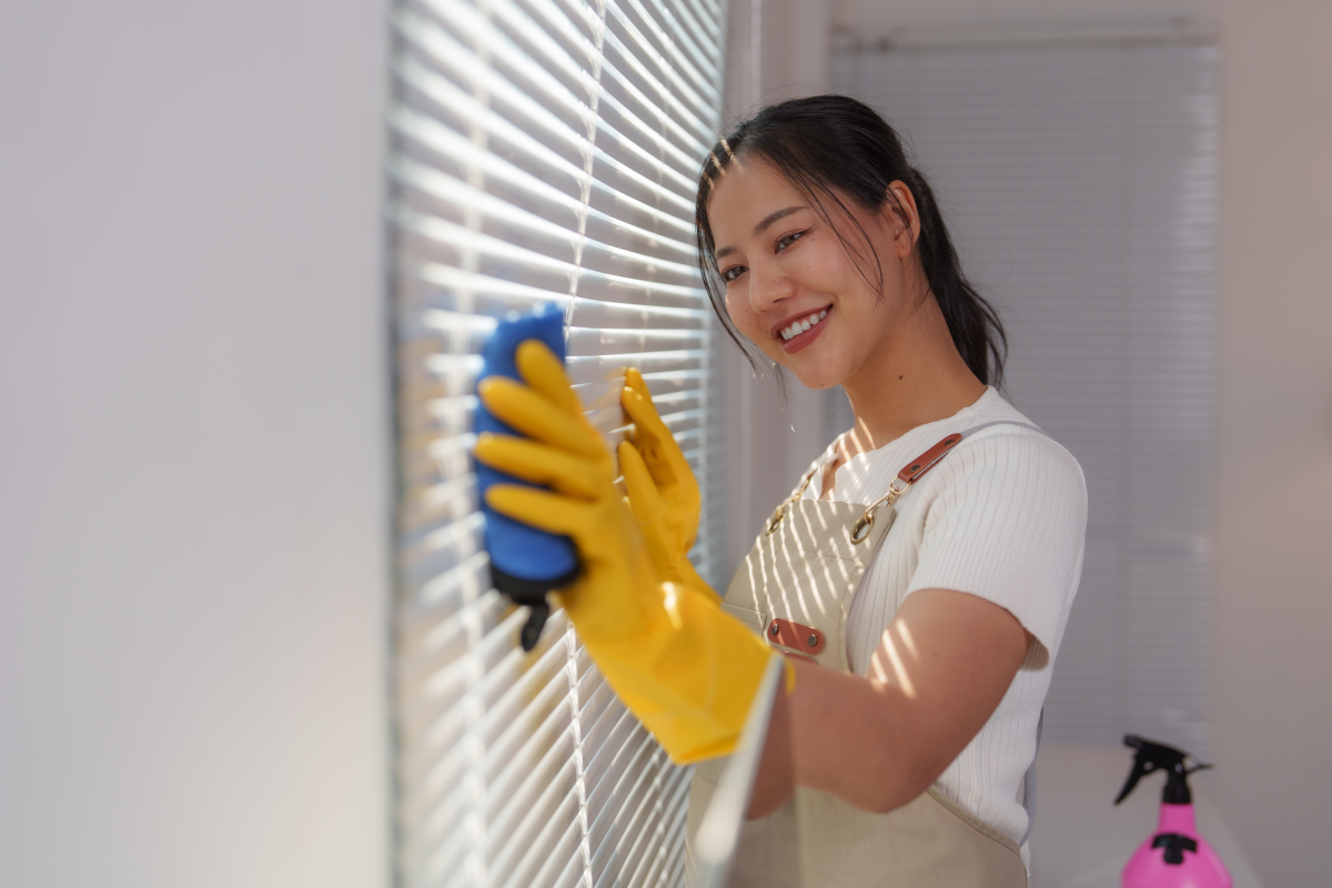 Someone cleaning the blinds in their home with a soft cloth