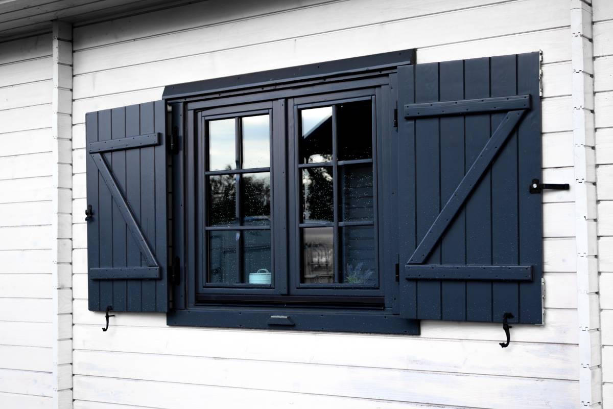 Elegant wooden window with dark shutters on a white house during daylight near Charleston and Beaufort, SC