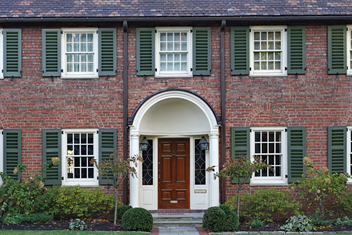 A large brick home with green colonial shutters