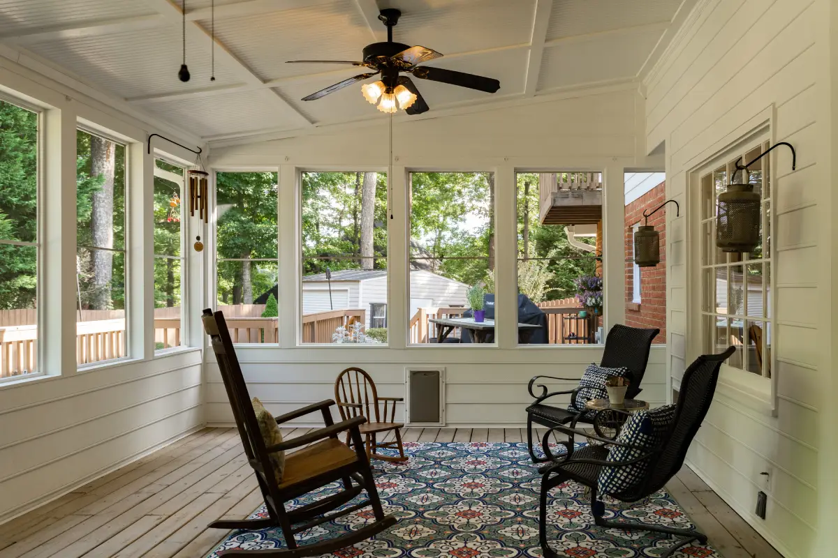  Sunroom with rocking chairs and large windows viewing wooded backyard